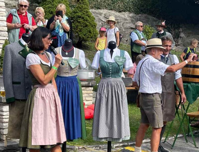 Die Leiterin vom Steirischen Heimatwerk vor ihren Trachten erklärt die Merkmale Steirischer Tracht.